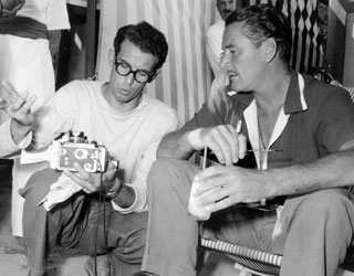 Showing his camera to Errol Flynn, Venice, 1953